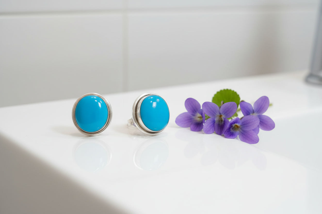 Pair of earrings with turquoise stones on a textured surface